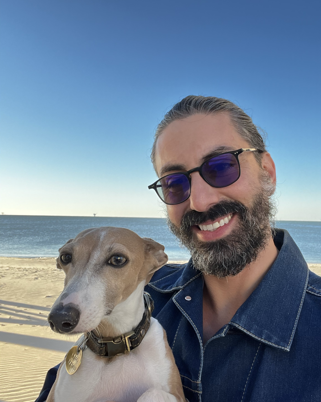 Joshua Blanco, founder of Voodoo Vodka, on the beach with his Italian Greyhound, Maxima.